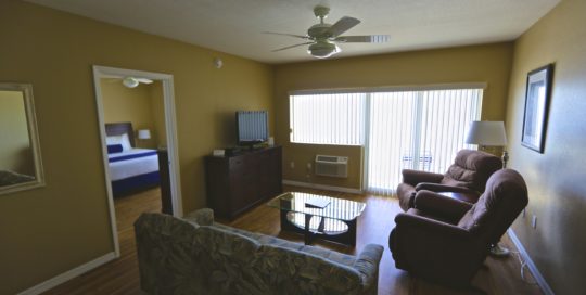 two recliners, sofa, dresser with television on top