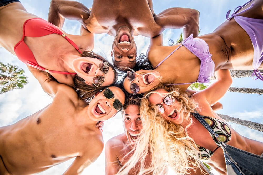 A group of friends peer down at the camera during their sunny spring break in Madeira Beach, FL.
